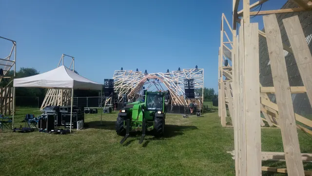 Six totems géants triangulaires autour du dancefloor pour accueillir la lumière et créer une scénographie immersive, décors en bois accrochés sur la structure et mise en place du gros module d’arche
