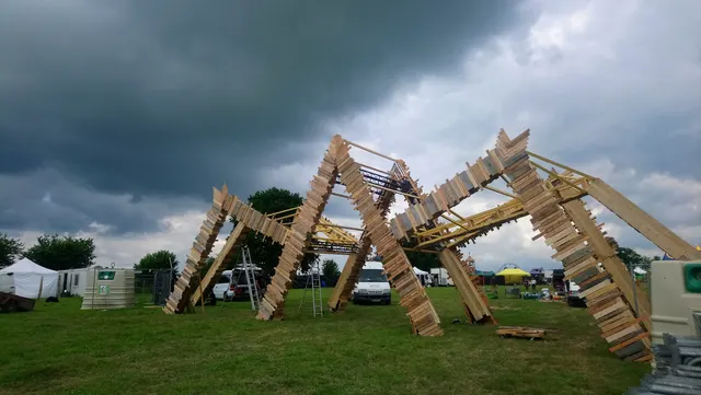 Arche d’entrée : structure principale en poutre, jambes en bois et habillage en planches de bois de différentes teintes et longueurs